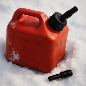 Small spare fuel canister standing in the snow next to a sled