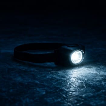 Bright headlamp beam cutting across dark night ice