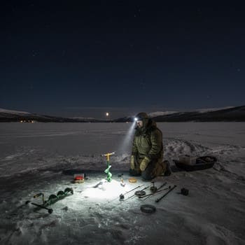Packed sled and headlamp beam during a late night return from the ice